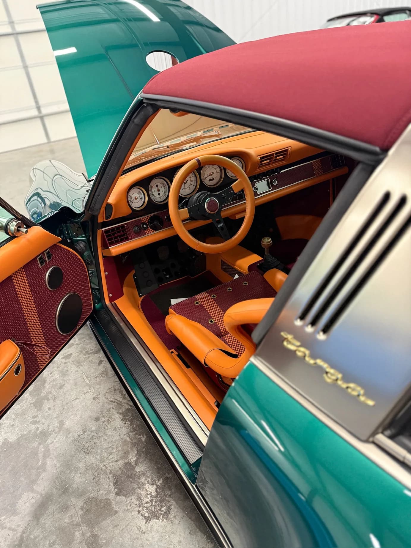 The driver's door open, steering wheel and dash visible against the green paint