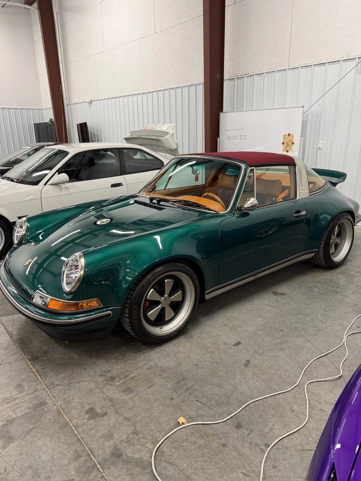 A wider front three-quarter view, other cars visible in the shop behind it