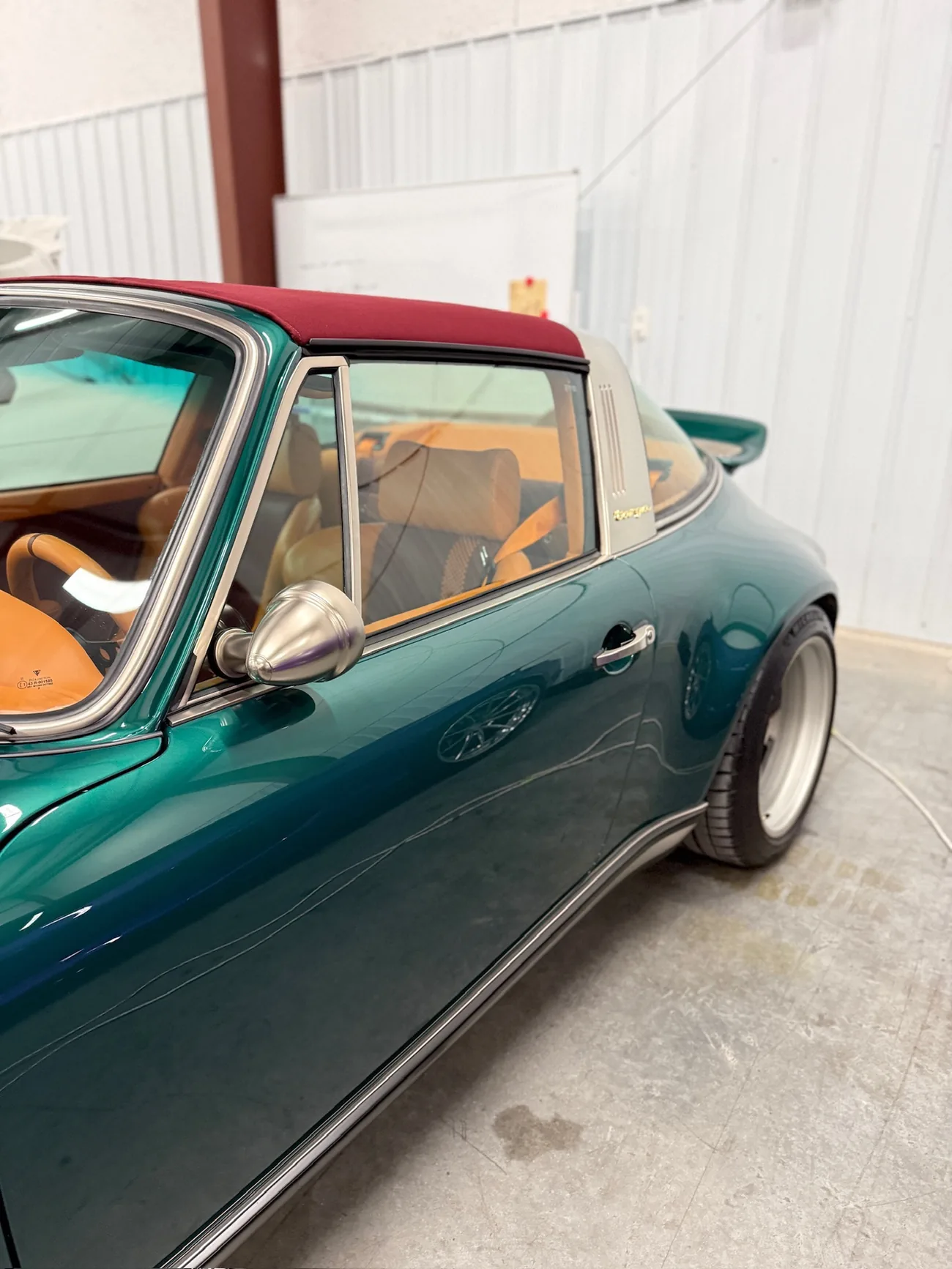 A brushed side mirror against the green paint, shallow depth of field
