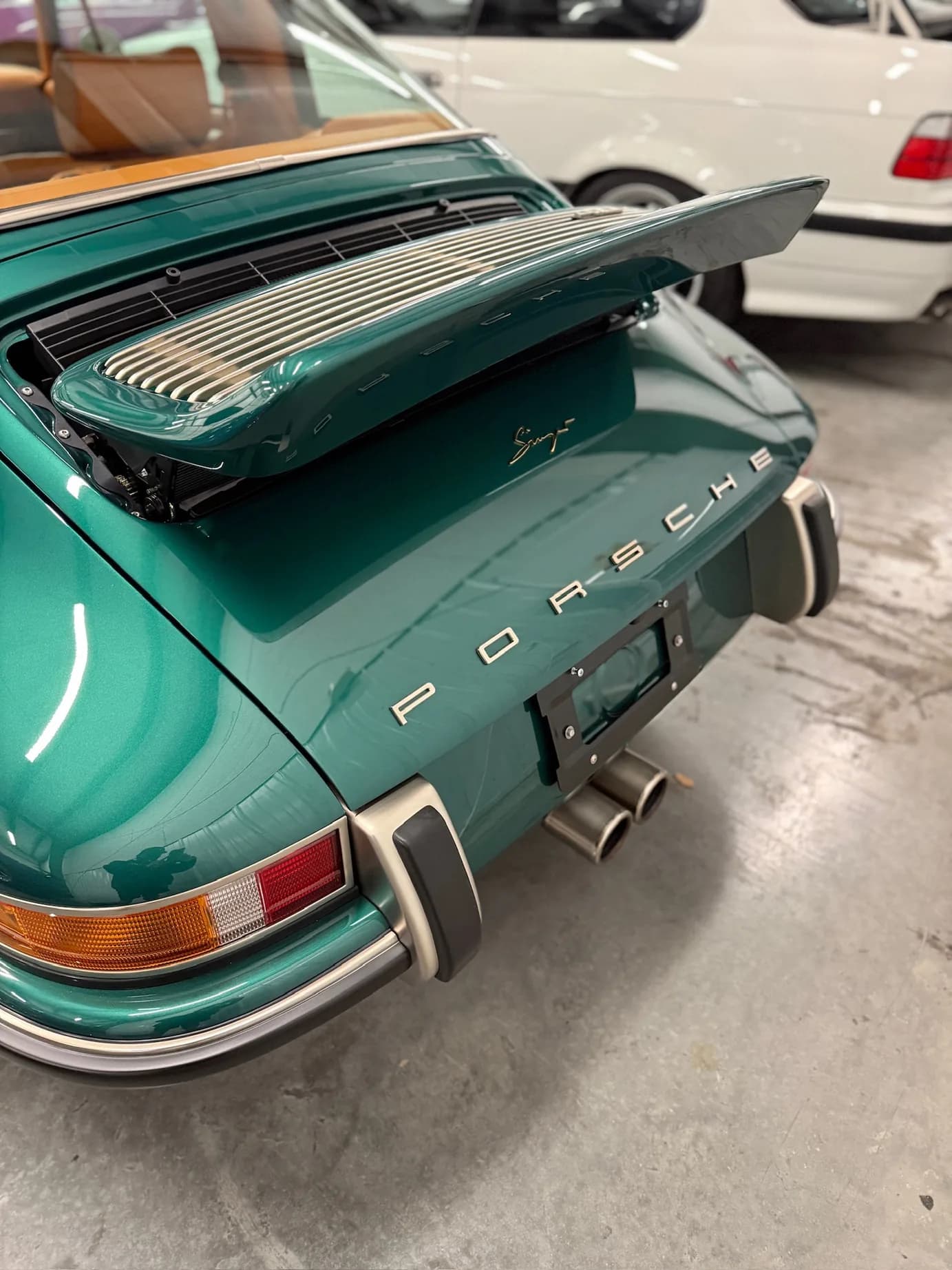 The rear deck with spoiler raised, dual center-exit exhaust tips, and the Porsche script
