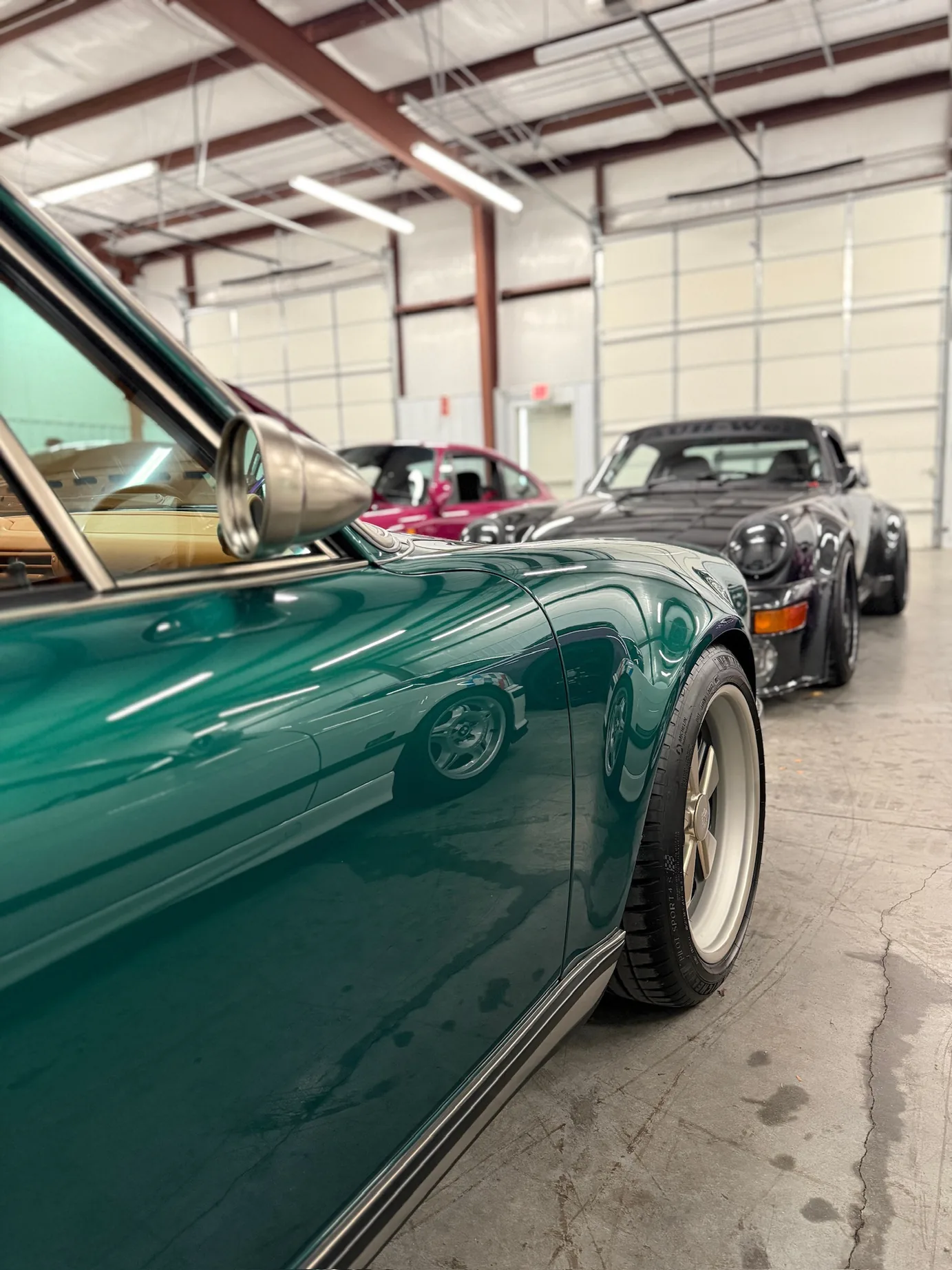 The Singer 911 in the foreground with an RWB-built 911 and other cars further back in the shop