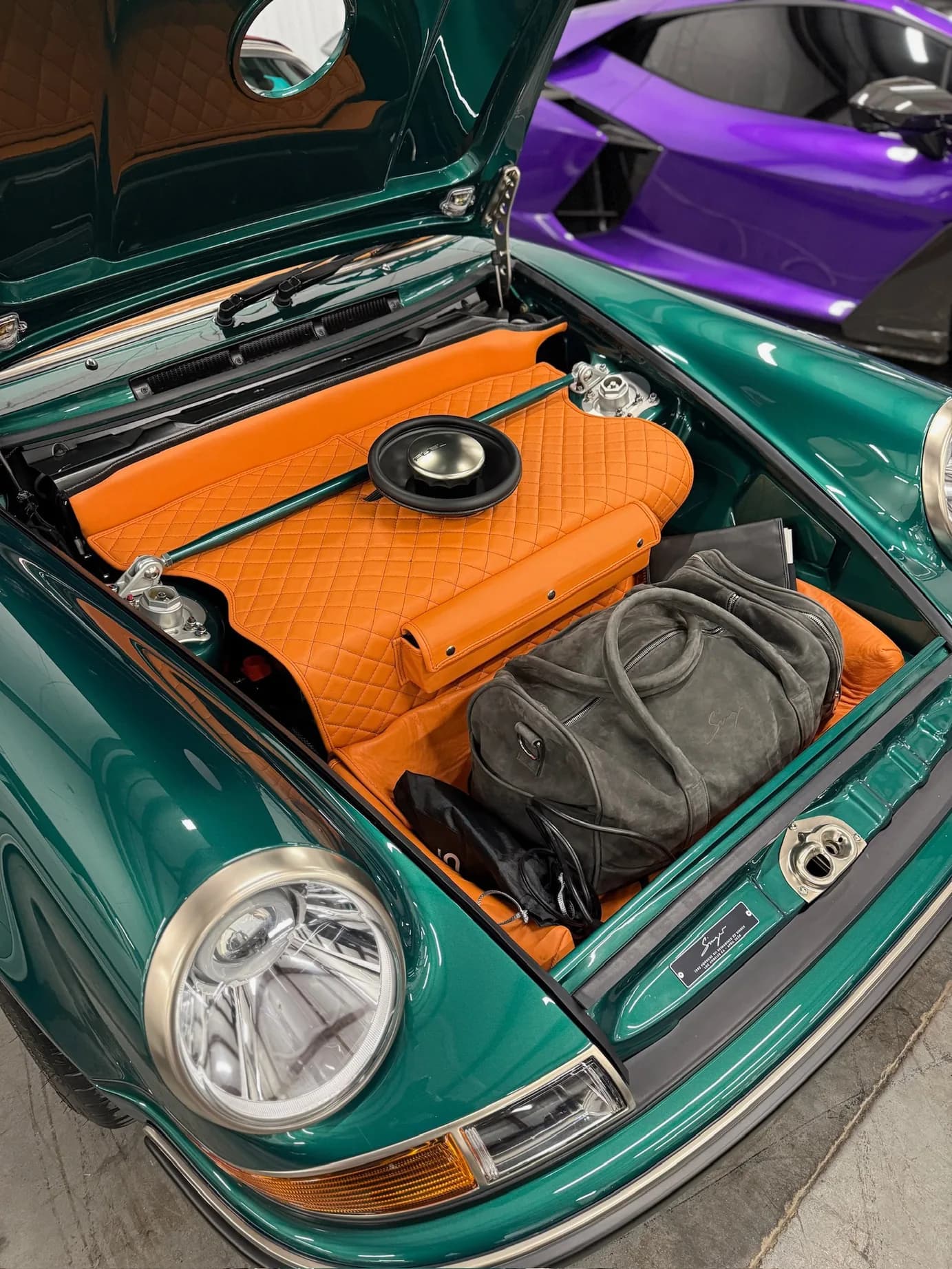 The front trunk, lined in quilted orange leather, with a travel bag and documents