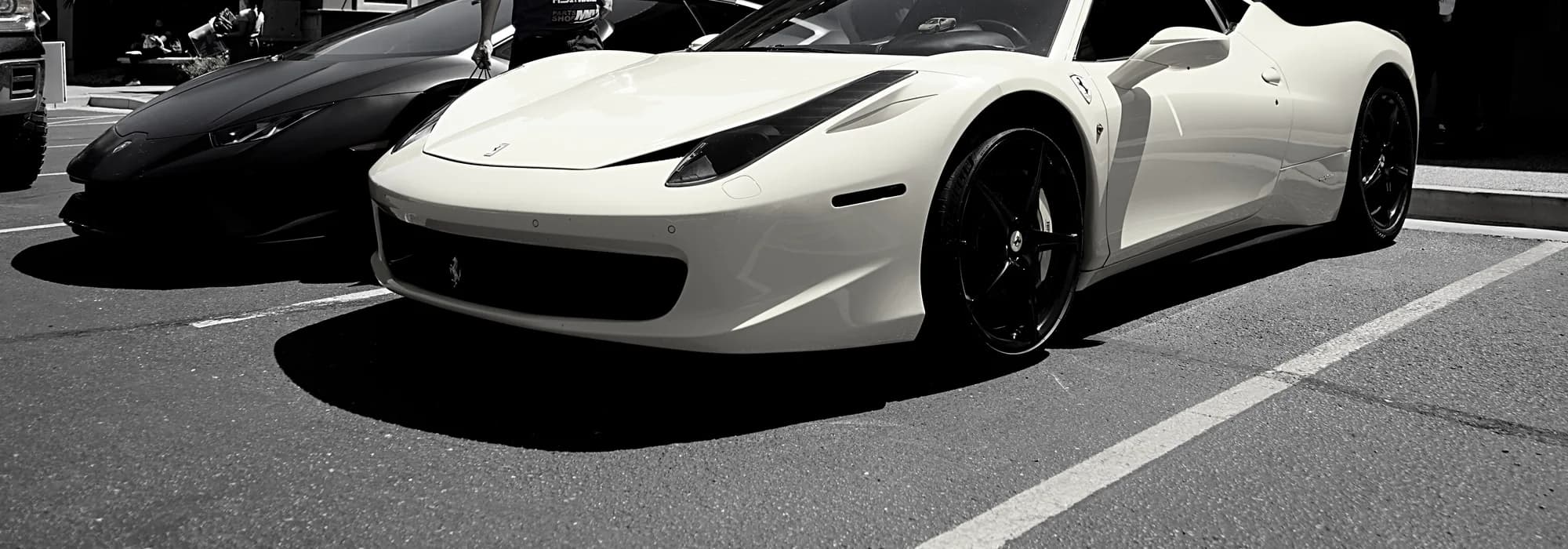 A white Ferrari 458 parked beside a black Lamborghini at one of our events