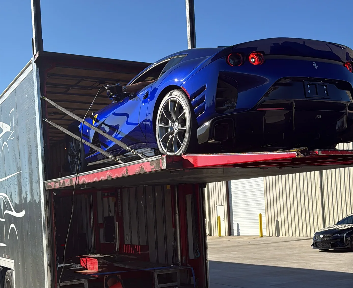 A Ferrari 812 Competizione backed off a transporter, rear glass replaced with a vented panel