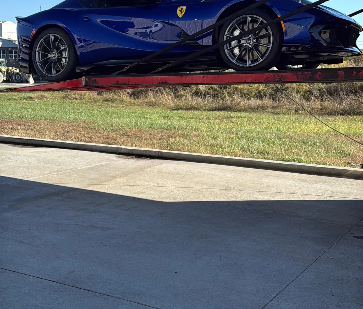 A side profile of the car on the transporter's ramp, outdoors in full sun